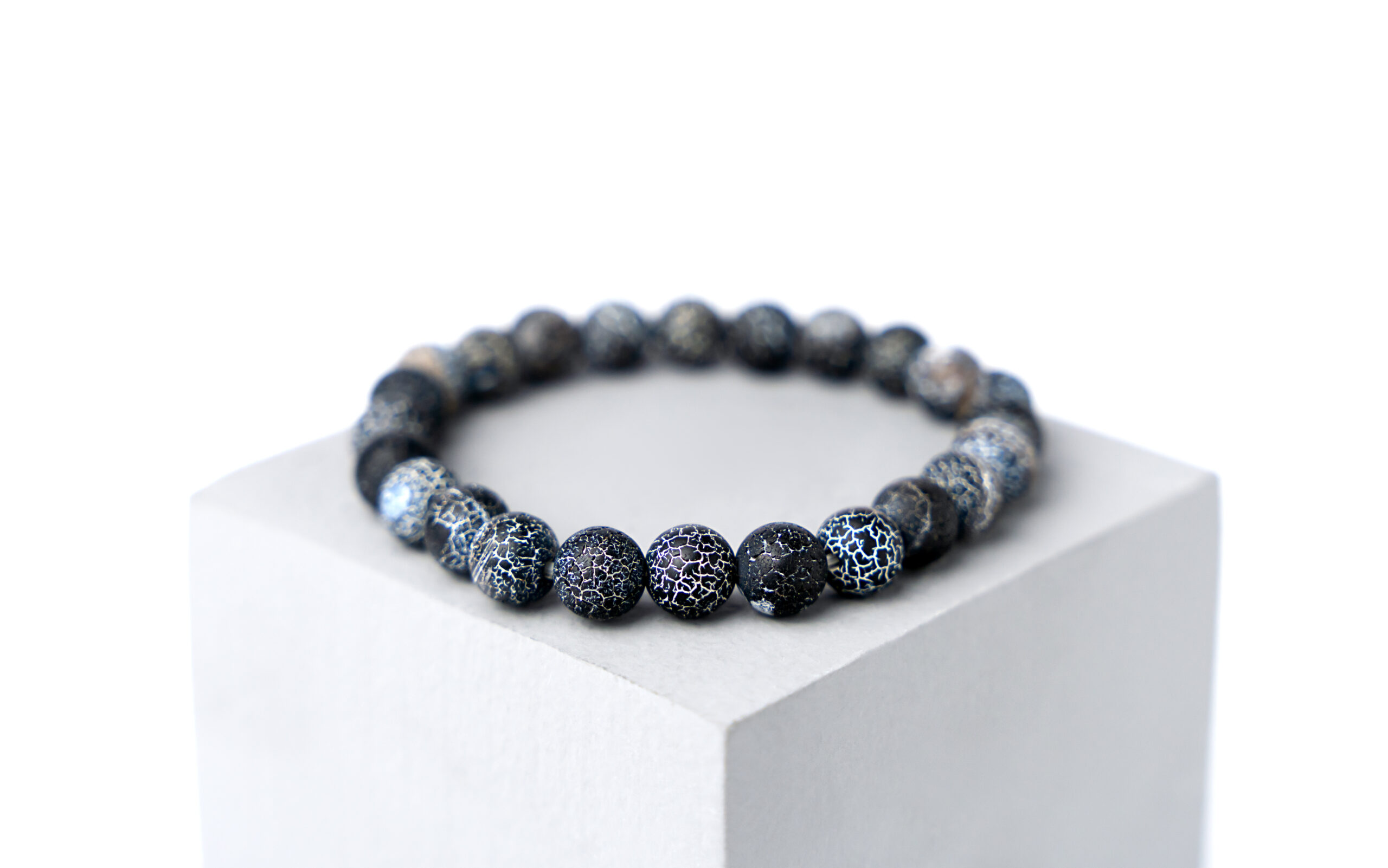 Natural stone bracelet on a gray podium on a white background. Close-up.